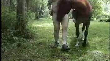 Guy banging a mare in the mouth near the woods